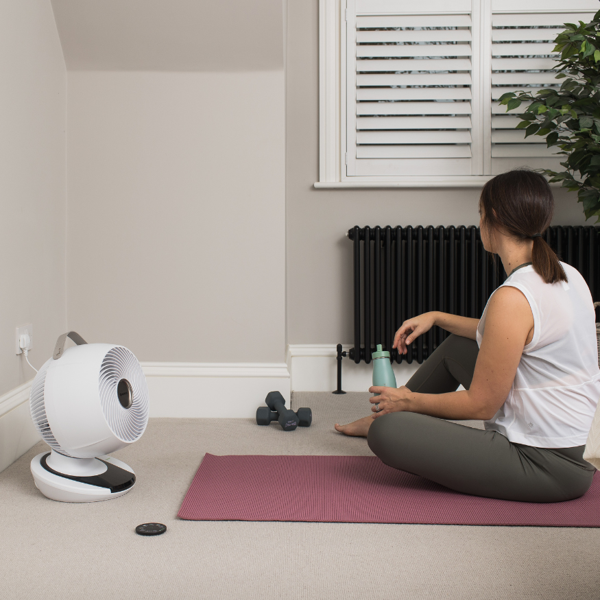 Woman setting up for home work out with the cooling MeacoFan 1056